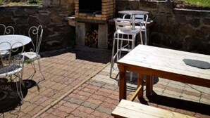 Un espace patio doté d’un four en briques, de sièges d’extérieur et d’un mur en pierre.