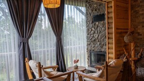 A cozy room with a stone fireplace, wooden furniture, and a large window with curtains. - Abant Pelit  (Bolu)