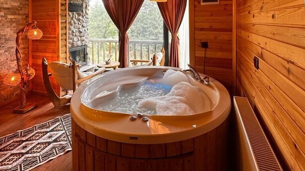 A wooden cabin interior with a hot tub, stone walls, and a view of the outdoors. - Abant Pelit  (Bolu)