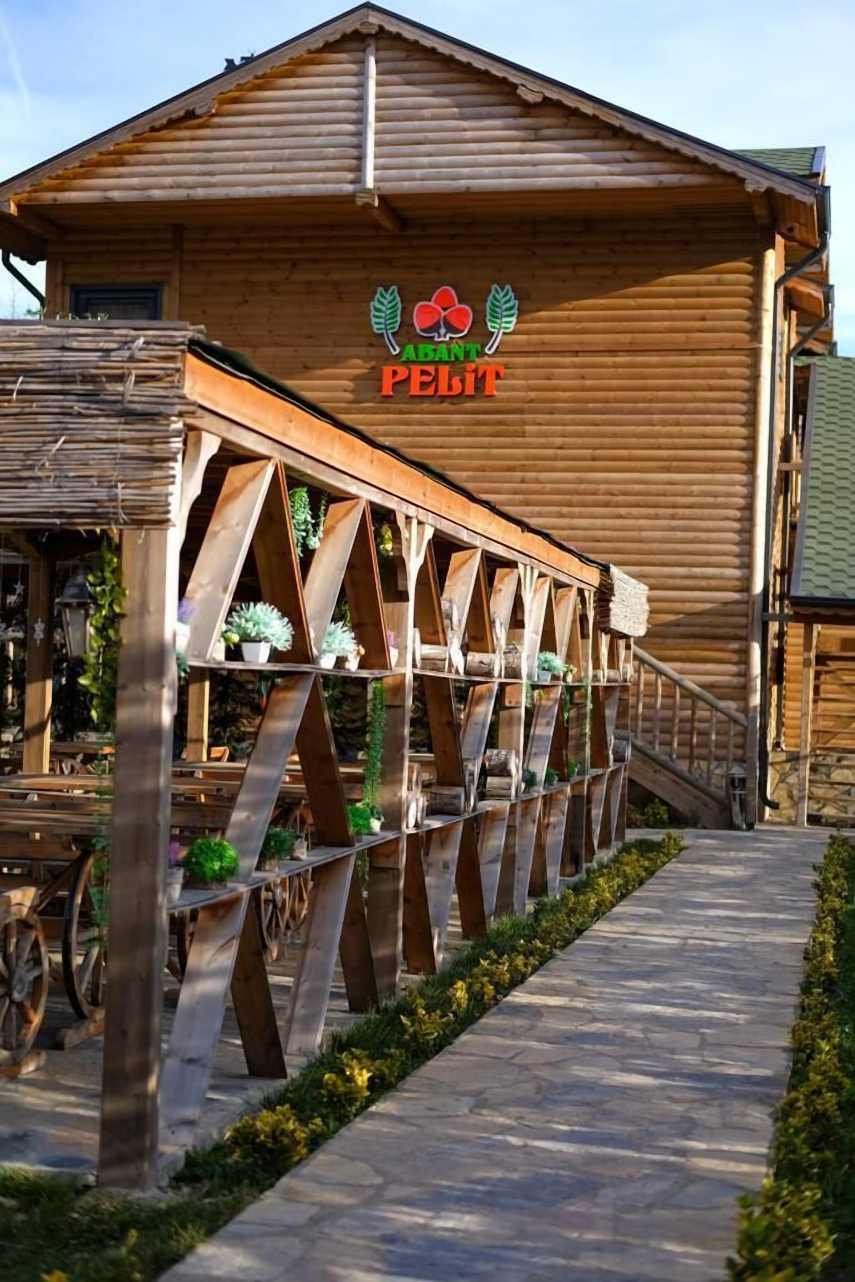 Um edifício de madeira com uma placa que diz 'ABAND PEELIT' e uma área de estar coberta ao ar livre com plantas.
