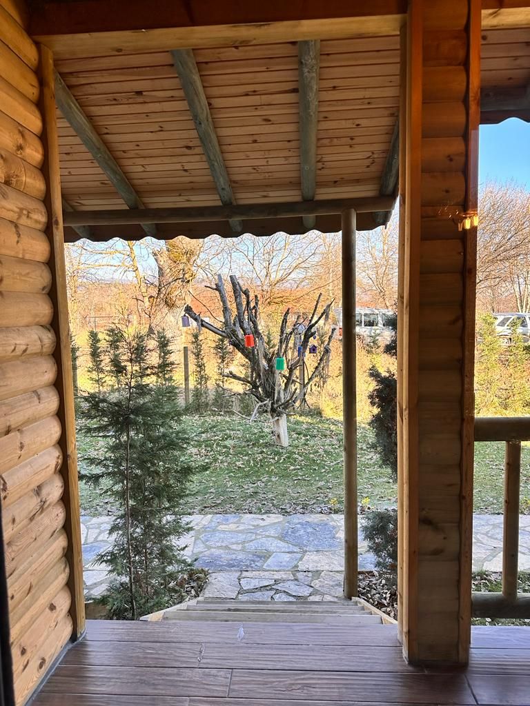 A wooden log cabin with a porch leading to a stone pathway.