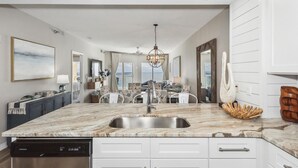 Una cocina moderna con encimera de mármol, pileta de acero inoxidable y muebles de cocina blancos.