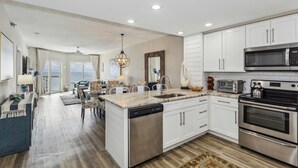 Una cocina moderna con armarios blancos, electrodomésticos de acero inoxidable y una isla central con lavavajillas.