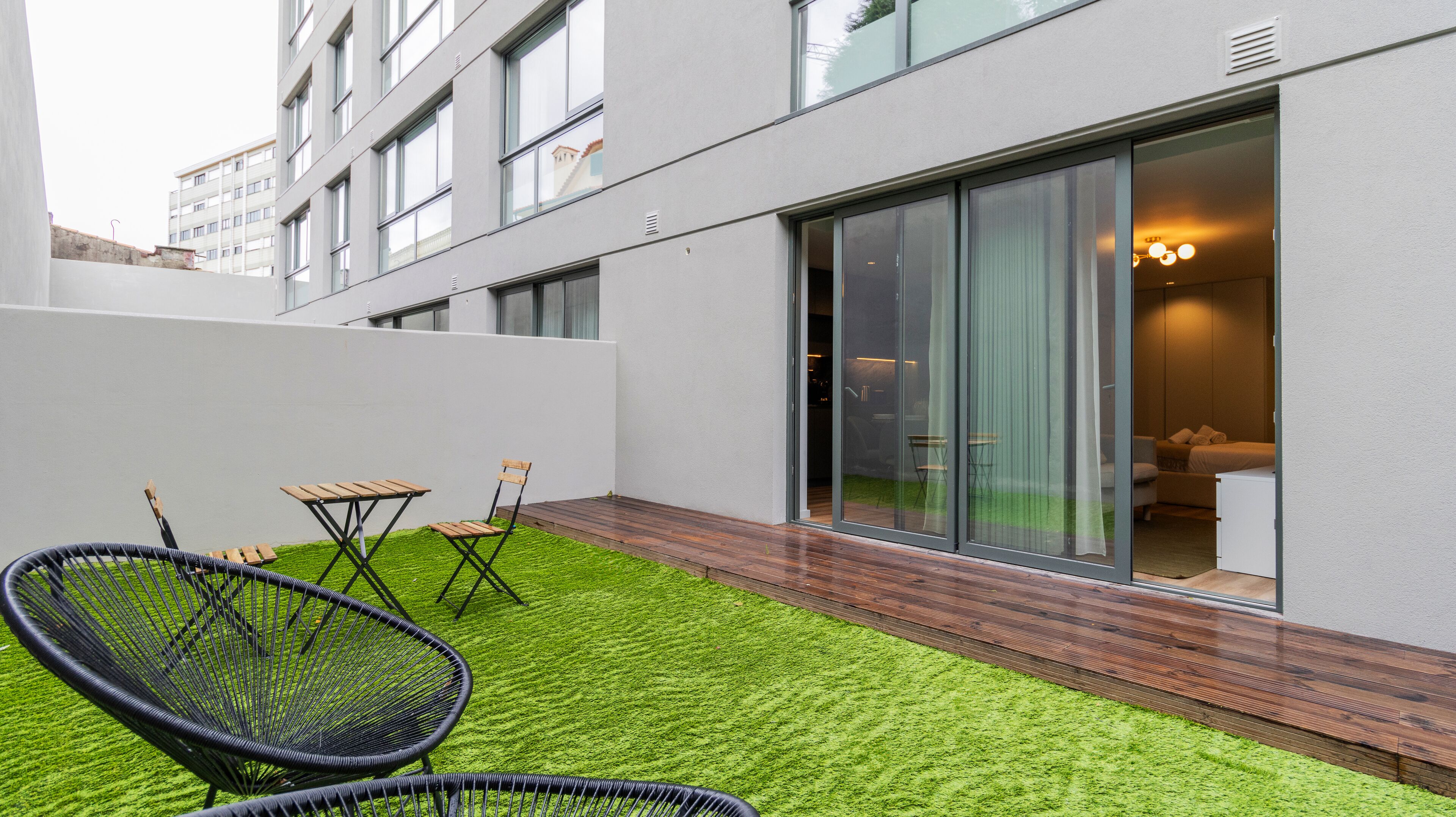 A modern building with a glass door leading to a room with a bed and a chair.
