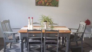A dining area with a wooden table, four chairs, a vase with a plant, and two candles.
