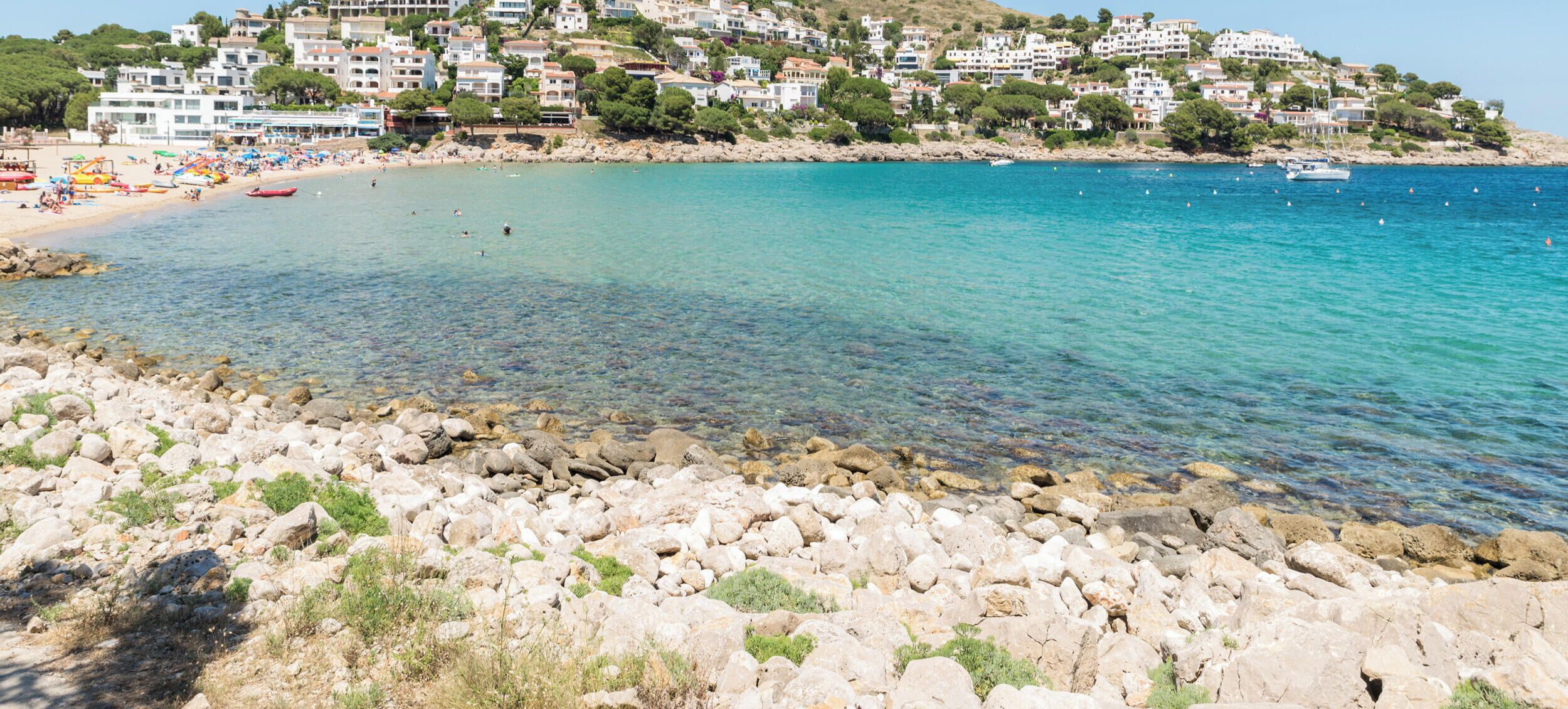 Un pueblo costero con edificios en una colina, con vistas a un mar azul y despejado.