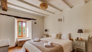 Ein gemütliches Schlafzimmer mit einem großen Bett, zwei Nachttischen, einem Fenster mit Blick und einer Holzbalkendecke.