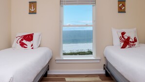 Ein Schlafzimmer mit zwei Betten, einem Fenster mit Meerblick und zwei Wandankern.