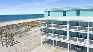 Ein Strandhotel mit mehreren Balkonen, ein Jeep vor dem Haus und ein Sandstrand.