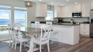 Una cocina moderna con armarios blancos, una mesa de comedor de madera y sillas.
