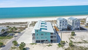 Un hotel frente a la playa con varias edificaciones, una playa arenosa y el océano al fondo.