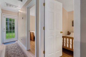 A hallway leading to a bedroom with a wooden bed and a small bedside table. - North Bay Tranquility Baileys Harbor Dog Friendly (Baileys Harbor)
