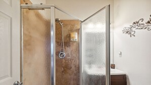 A bathroom with a glass shower enclosure, a toilet, and a sink. - Charming Pu'ukala Sunset - Near Hiking And Golf 1 Bedroom Home by RedAwning (Kailua-Kona)