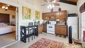 A compact kitchen with wooden cabinets, a microwave, stove, and a ceiling fan. - Charming Pu'ukala Sunset - Near Hiking And Golf 1 Bedroom Home by RedAwning (Kailua-Kona)