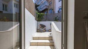 A narrow outdoor staircase leading to a balcony with a wicker chair and a small table. - Bombarda 32 (Lisbon)
