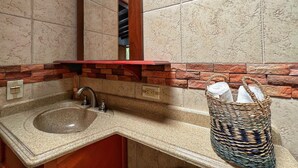 Un baño con lavamanos de granito, un espejo y una pared de ladrillo rojo.