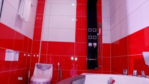 A bathroom with red and white tiles, a black shower panel, and a white bathtub. - MATCHEU PALACE HÔTEL  (Yaoundé)