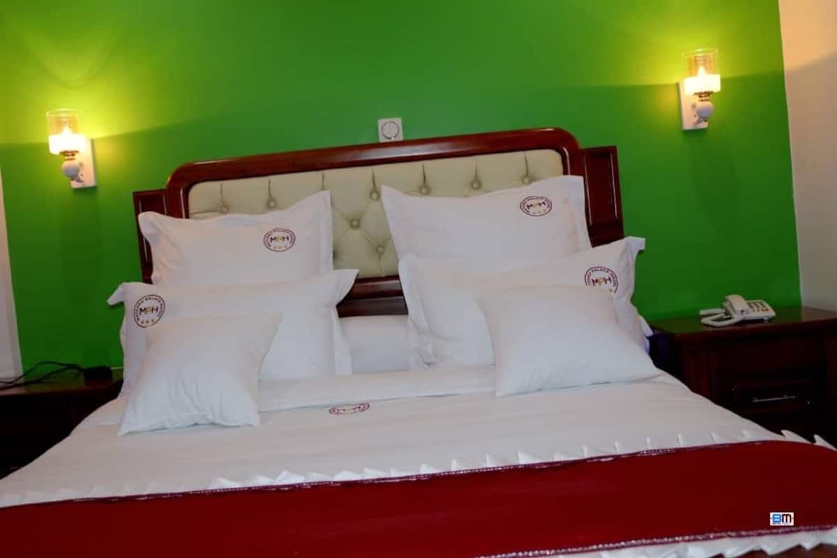 A bed with white bedding and pillows, a wooden headboard, and two bedside lamps.