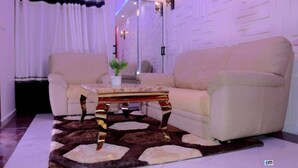 A living room with a beige sofa, a patterned rug, and a wooden coffee table. - MATCHEU PALACE HÔTEL  (Yaoundé)