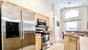 Una cocina moderna con electrodomésticos de acero inoxidable, armarios de madera y un amplio ventanal que proporciona luz natural.