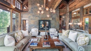 A spacious living room with a stone fireplace, wooden beams, and a chandelier. - Robber's Roost- Sprawling, Ski In/Out, Arcade, Pool Table, & More! (Mountain Village)
