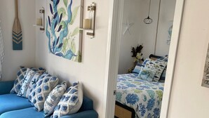 Een kamer met een blauwe bank, een bed met bloemenbeddengoed, een muur met een bladpatroon en een zeester decoratie.