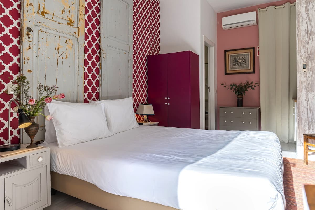 A bedroom with a bed, a nightstand, a dresser, and a wall-mounted air conditioner.