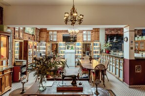 A cozy library with wooden bookshelves, a central table with chairs, and a vintage sewing machine. - Labor Alliance Residence by LovelyStay (Lisbon)