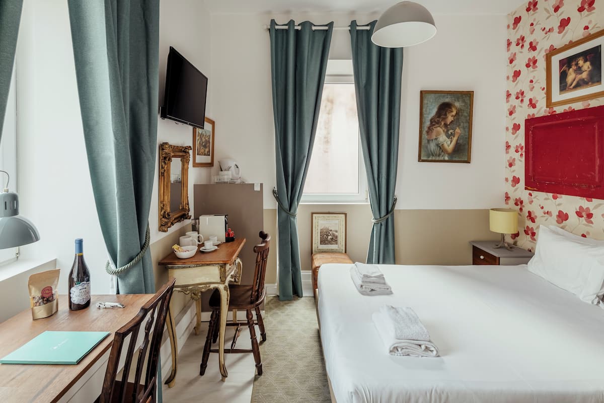 A hotel room with a bed, desk, chair, TV, and curtains.