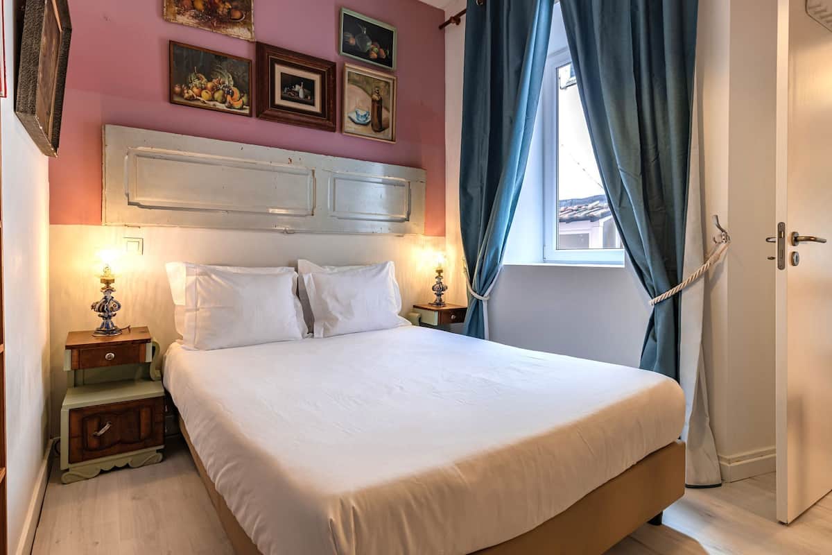 A neatly made bed with white linens, a wooden headboard, and two bedside tables with lamps.