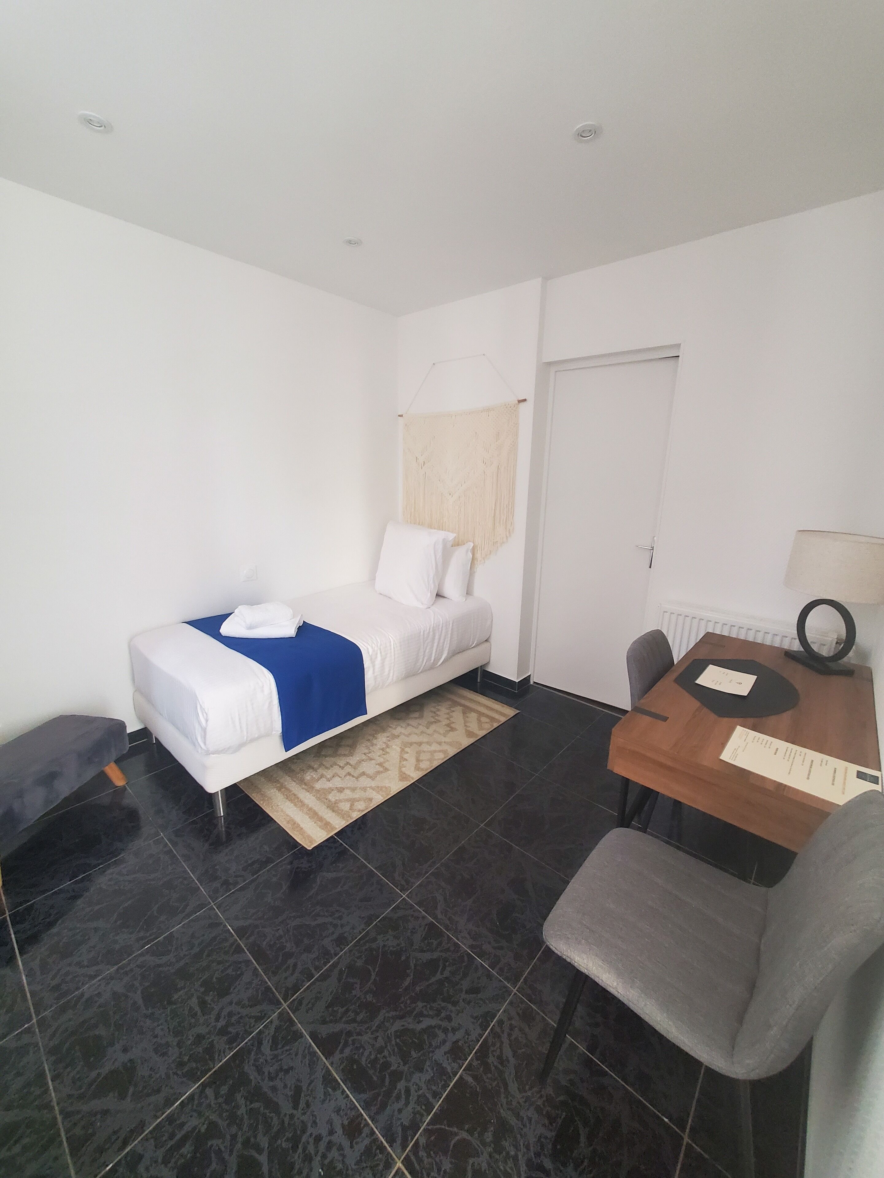 A hotel room with a bed, a desk, a chair, and a small table.