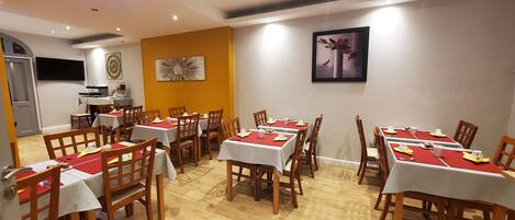 Un comedor con varias mesas y sillas, una zona de cocina y una obra de arte colgada en la pared.