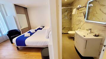 A hotel room with a bed, a bathroom with a sink and mirror, and a shower.