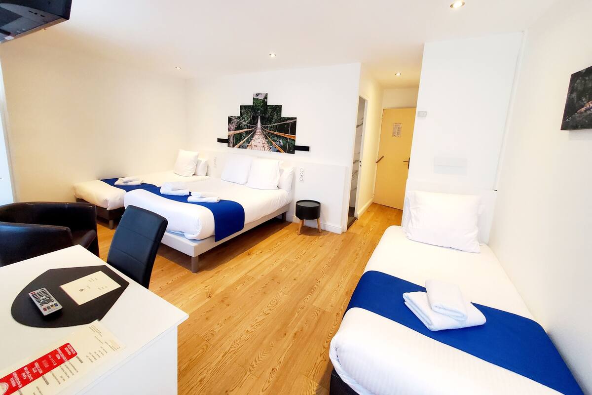 A hotel room with a bed, a desk with a remote control, and a small table with a menu.