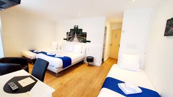 A hotel room with a bed, a desk with a remote control, and a small table with a menu.