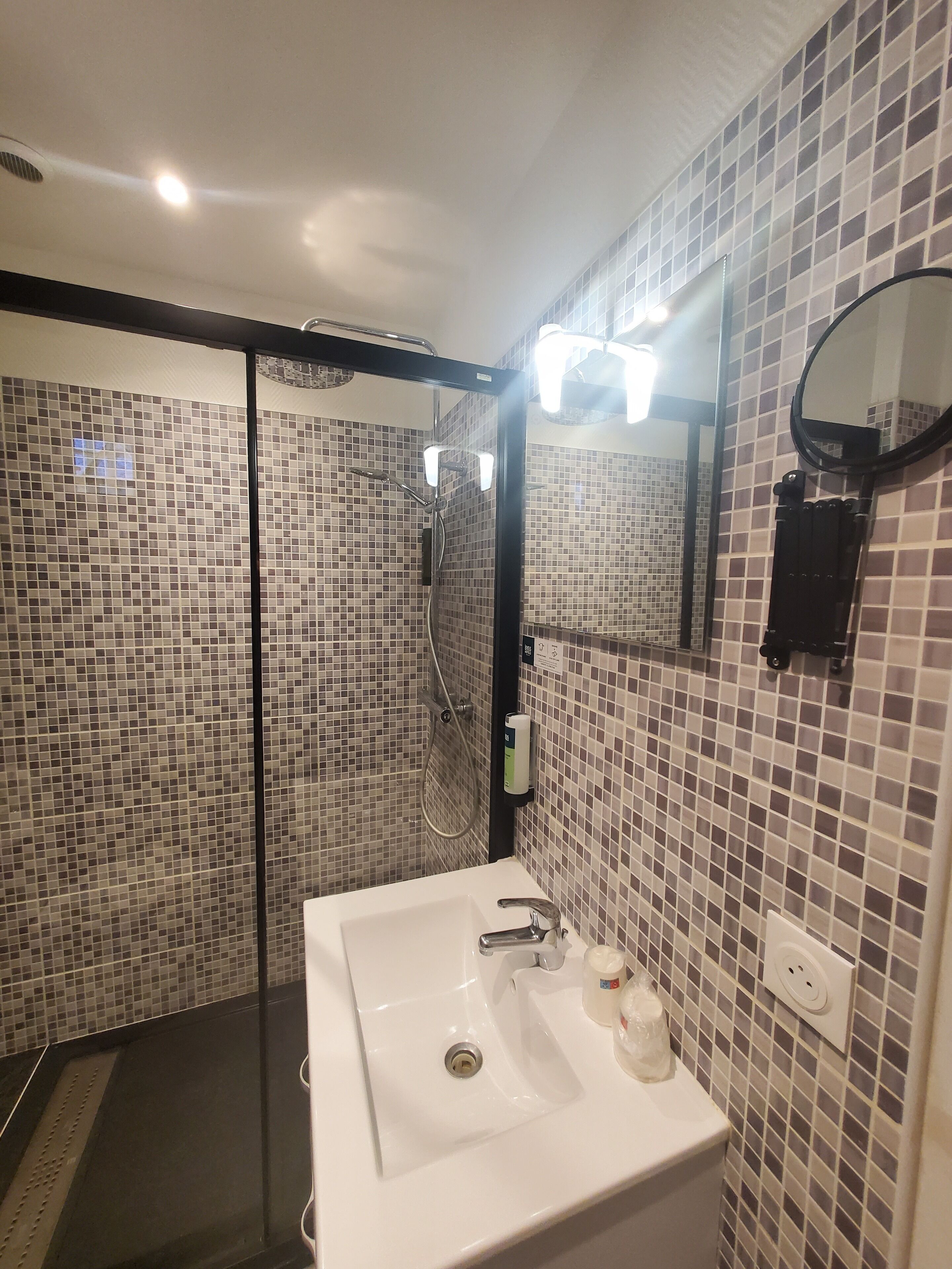 Ein Badezimmer mit Duschkabine, Waschbecken und Spiegel.
