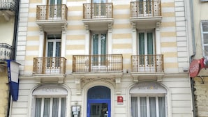 A hotel with a blue and white facade, multiple balconies, and a central entrance with a blue door.
