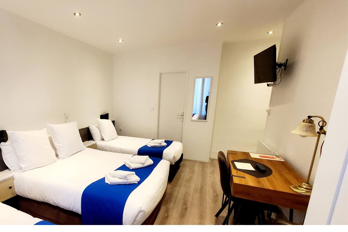 A hotel room with two beds, a desk, and a TV mounted on the wall.
