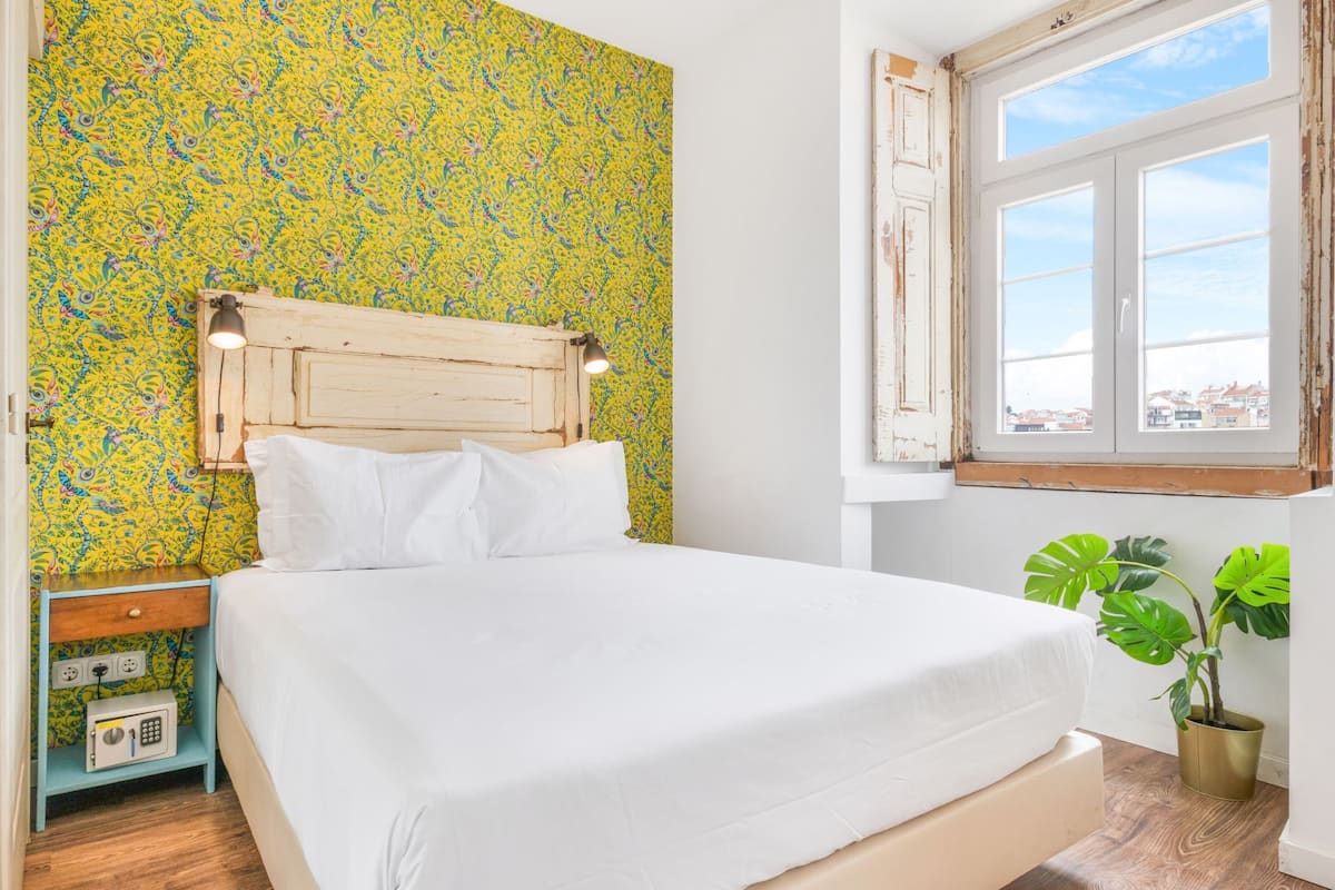 A bed with white bedding, a wooden headboard, and a nightstand with a radio.