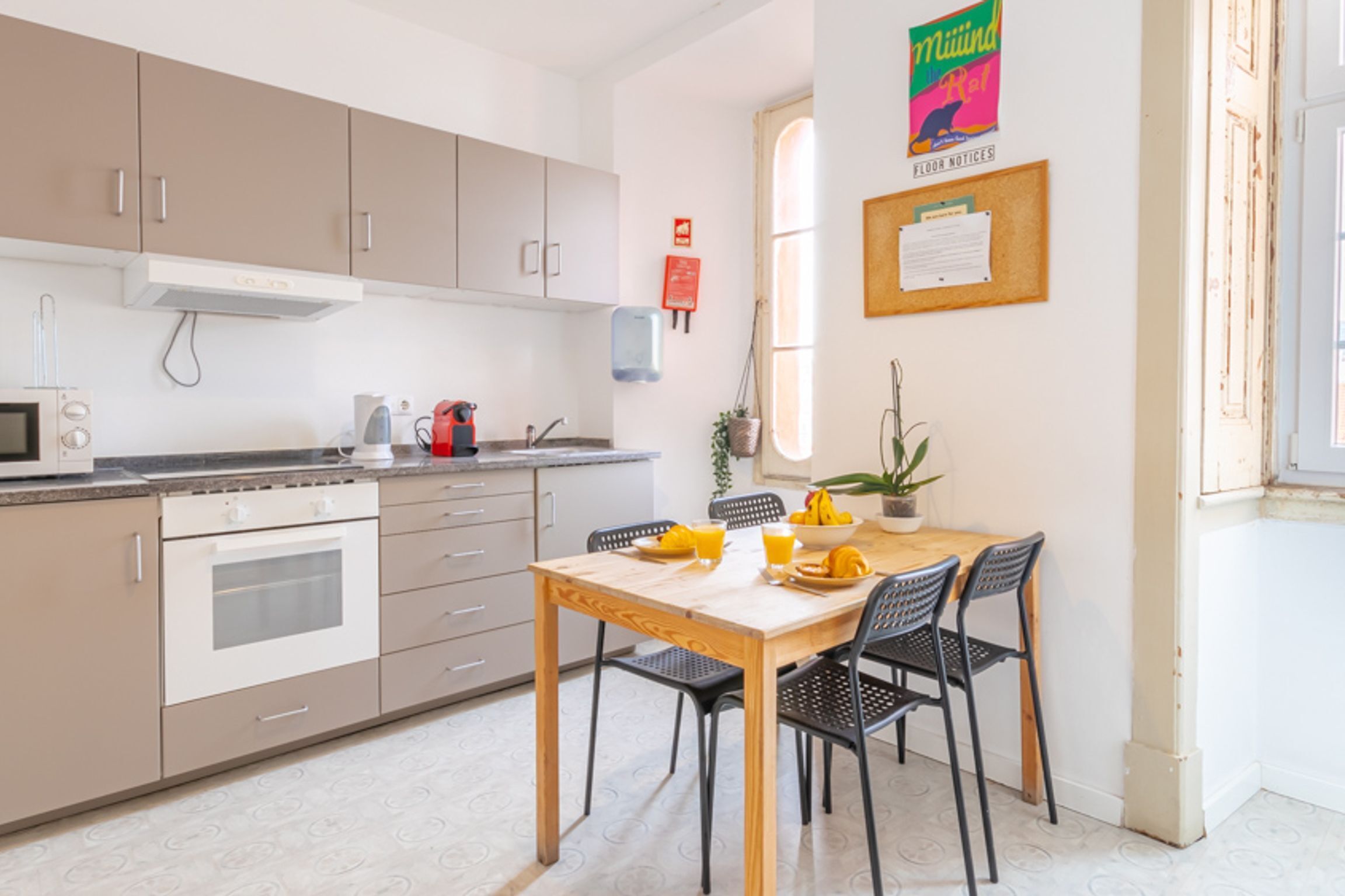 Una cocina moderna con comedor, que incluye una mesa y sillas de madera, un microondas y una tetera.