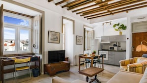 Un soggiorno con una scrivania in legno, una televisione, un divano e un'area pranzo con sedie e un tavolo.