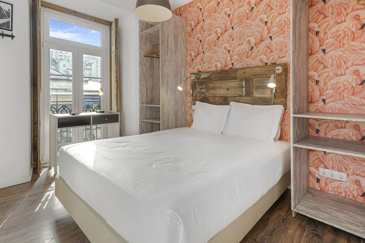 A bedroom with a large bed, wooden headboard, and a wooden shelf unit.