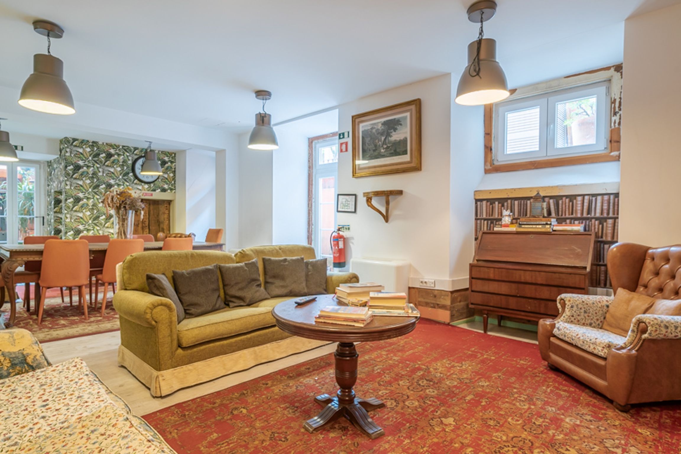 Un salon chaleureux avec un canapé vert, un fauteuil marron, une table basse ronde et une bibliothèque.