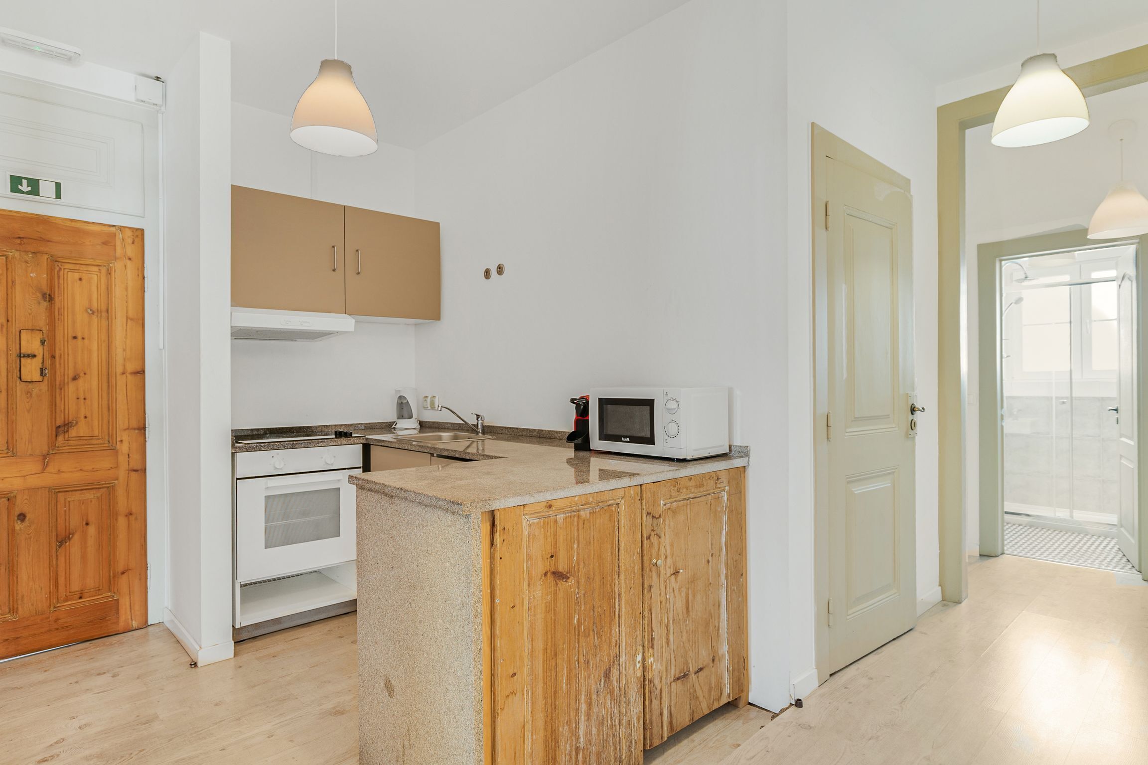 A kitchen with wooden cabinets, a microwave, and a sink.