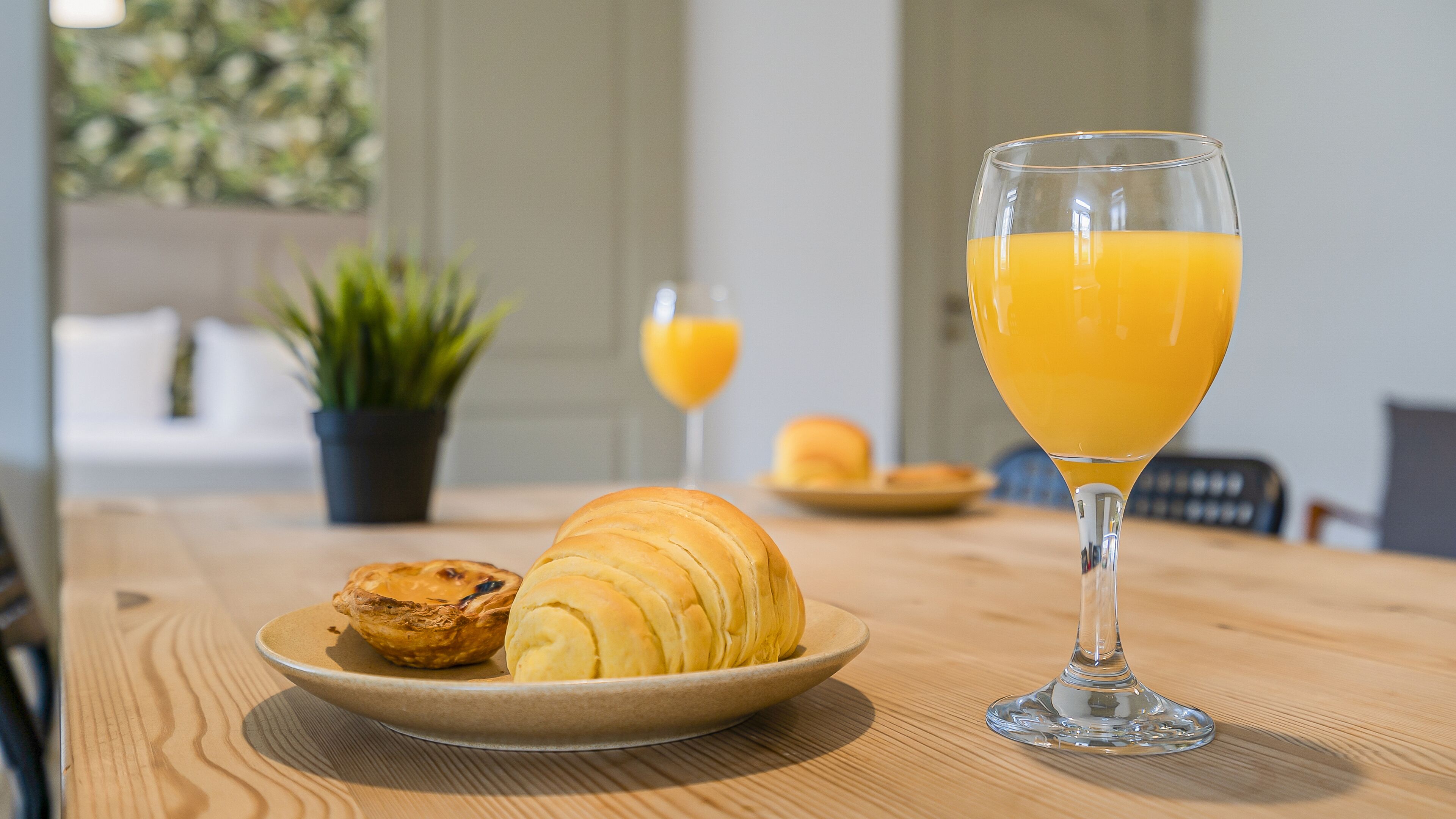 Ein Frühstückstisch mit einem Croissant und einem Glas Orangensaft.