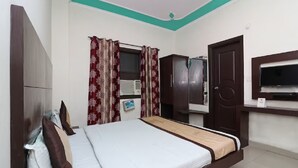 A bedroom with a bed, wardrobe, TV, and an air conditioning unit.