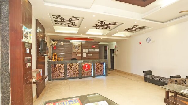 A hotel reception area with a reception desk, a waiting area with a sofa and a coffee table, and a ceiling with decorative patterns.