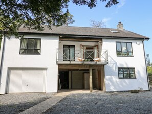 A two-story white house with a balcony, a garage, and a gravel driveway. - The Coach House at Plas Dolguog (Machynlleth)