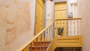 A staircase with yellow railings and doors, a marble wall, and a sign with the letter 'AL'.