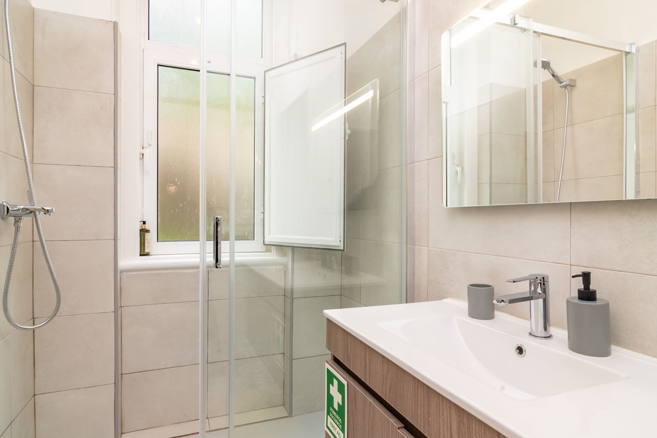 A modern bathroom with a glass shower enclosure, a sink with a mirror, and a cabinet.